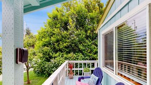 Eine Veranda mit zwei Stühlen, einem Tisch, einem Blumentopf und einem Fenster mit Jalousien.