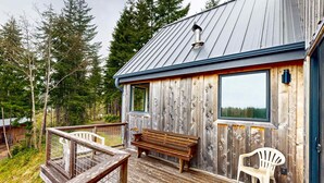 Eine Holzhütte mit einer Terrasse, einer Bank und einem Stuhl.