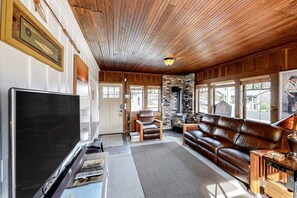 Ein Wohnzimmer mit Fernseher, Ledersofa und Kamin.