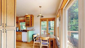 Una cucina con mobili in legno, un tavolo da pranzo, sedie e una finestra con vista su un patio.