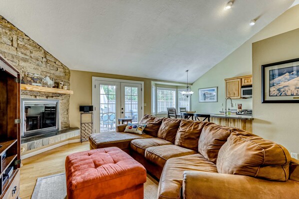 A cozy living room with a stone fireplace, a sectional sofa, and a television.
