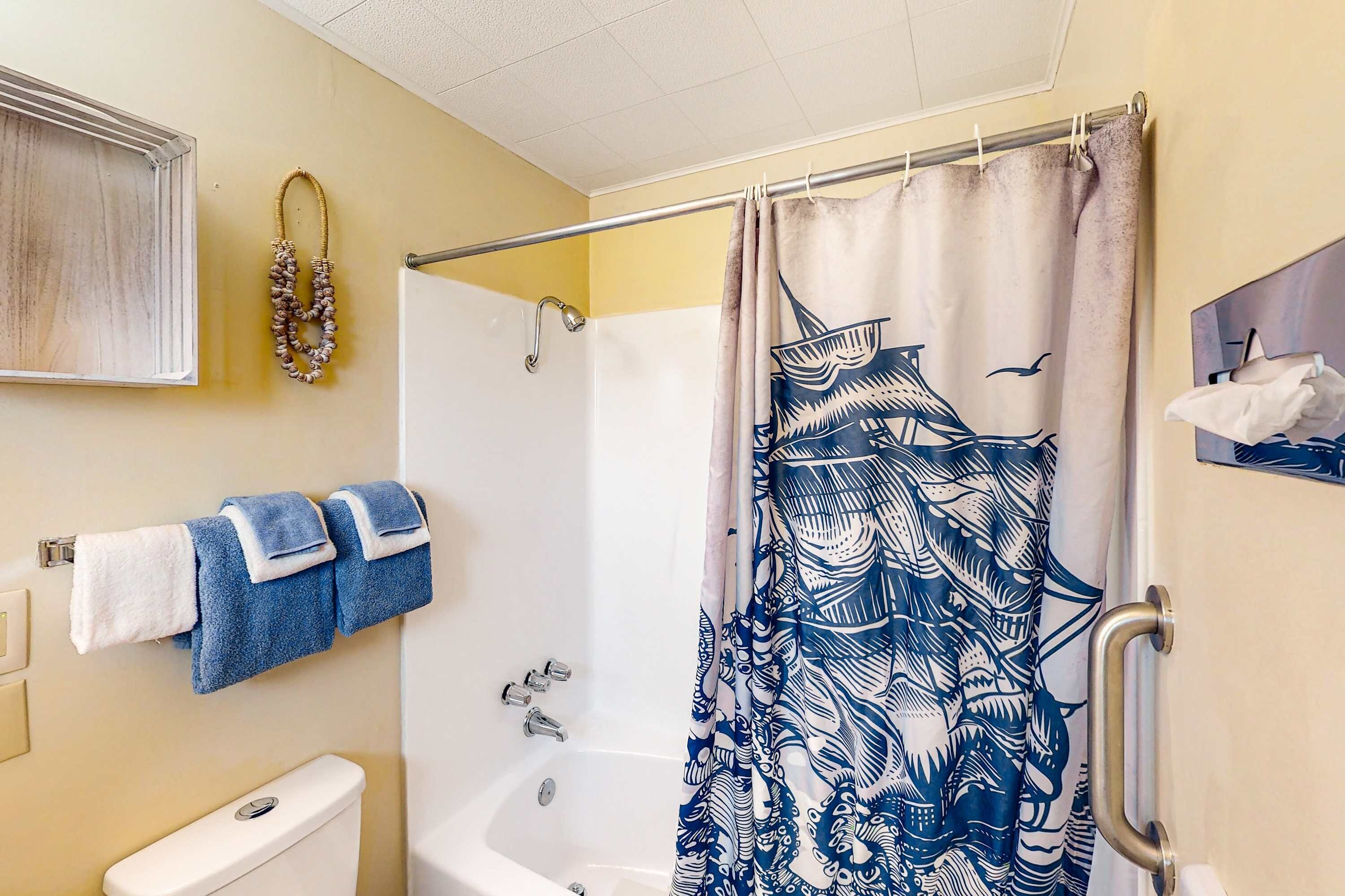 A bathroom with a bathtub, a toilet, and a shower curtain with a bird pattern.