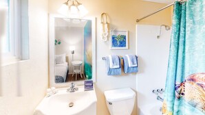 A bathroom with a sink, toilet, and shower curtain. - 4 Studios walkable to downtown, Dog Friendly, WiFi (Bandon)