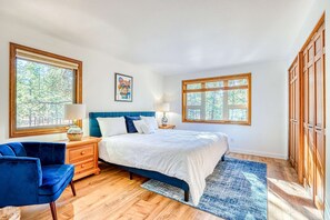 Ein Schlafzimmer mit einem Bett, zwei Nachttischen, einem kleinen Tisch, einem blauen Stuhl und Holzböden.