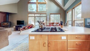 A modern kitchen with a large island, wooden cabinets, and a high ceiling with skylights. - Beautiful & spacious home with a private hot tub, fast WiFi, AC, & SHARC access (Sunriver)