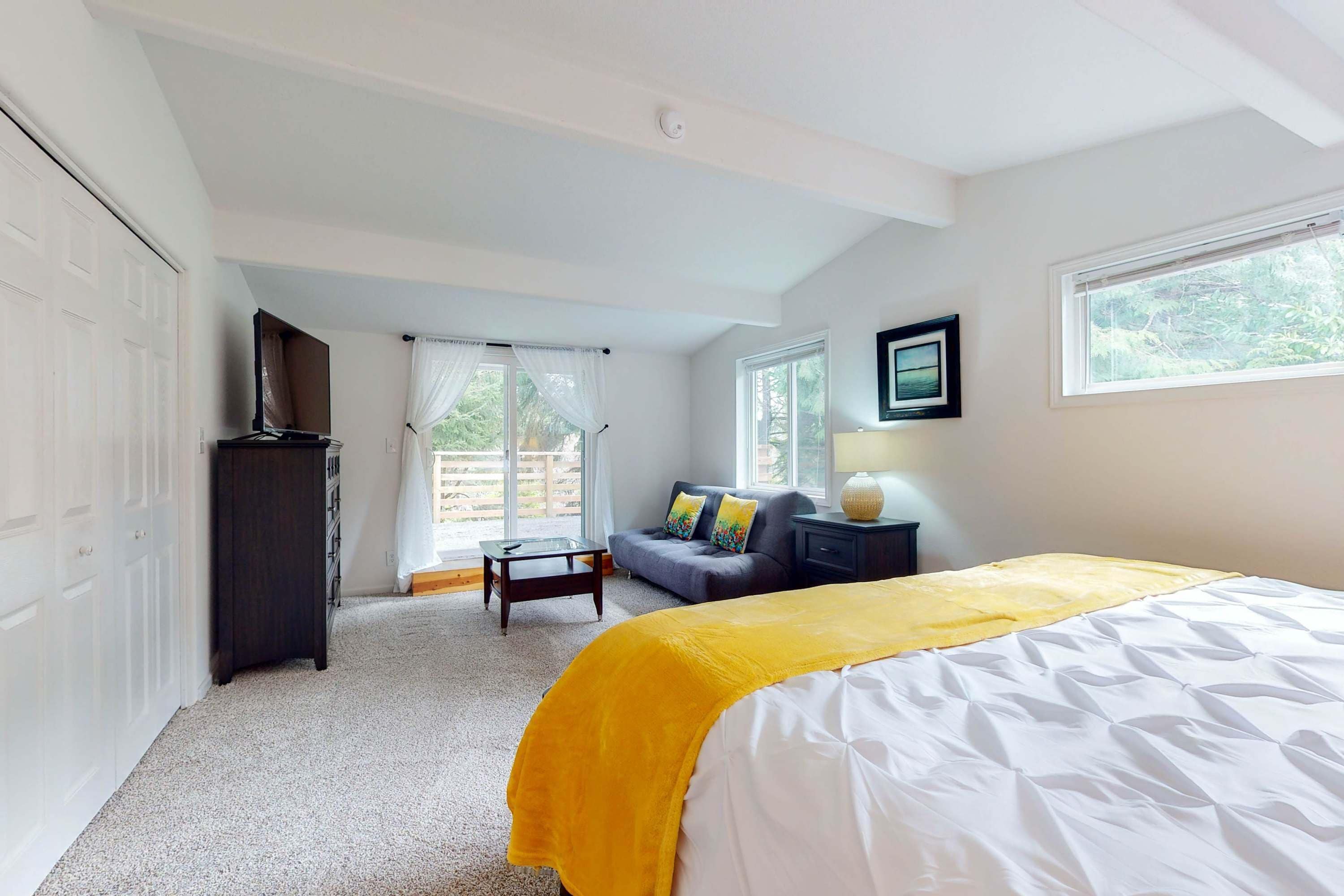 A bedroom with a bed, a sofa, a desk, and a window.