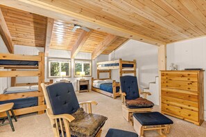 A room with wooden bunk beds, a wooden dresser, and a chair with a cushion. - Newly remodeled cabin-style condo near skiing & attractions - dogs welcome (Government Camp)