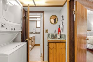 A laundry area with a washing machine, a sink, and a mirror. - Newly remodeled cabin-style condo near skiing & attractions - dogs welcome (Government Camp)