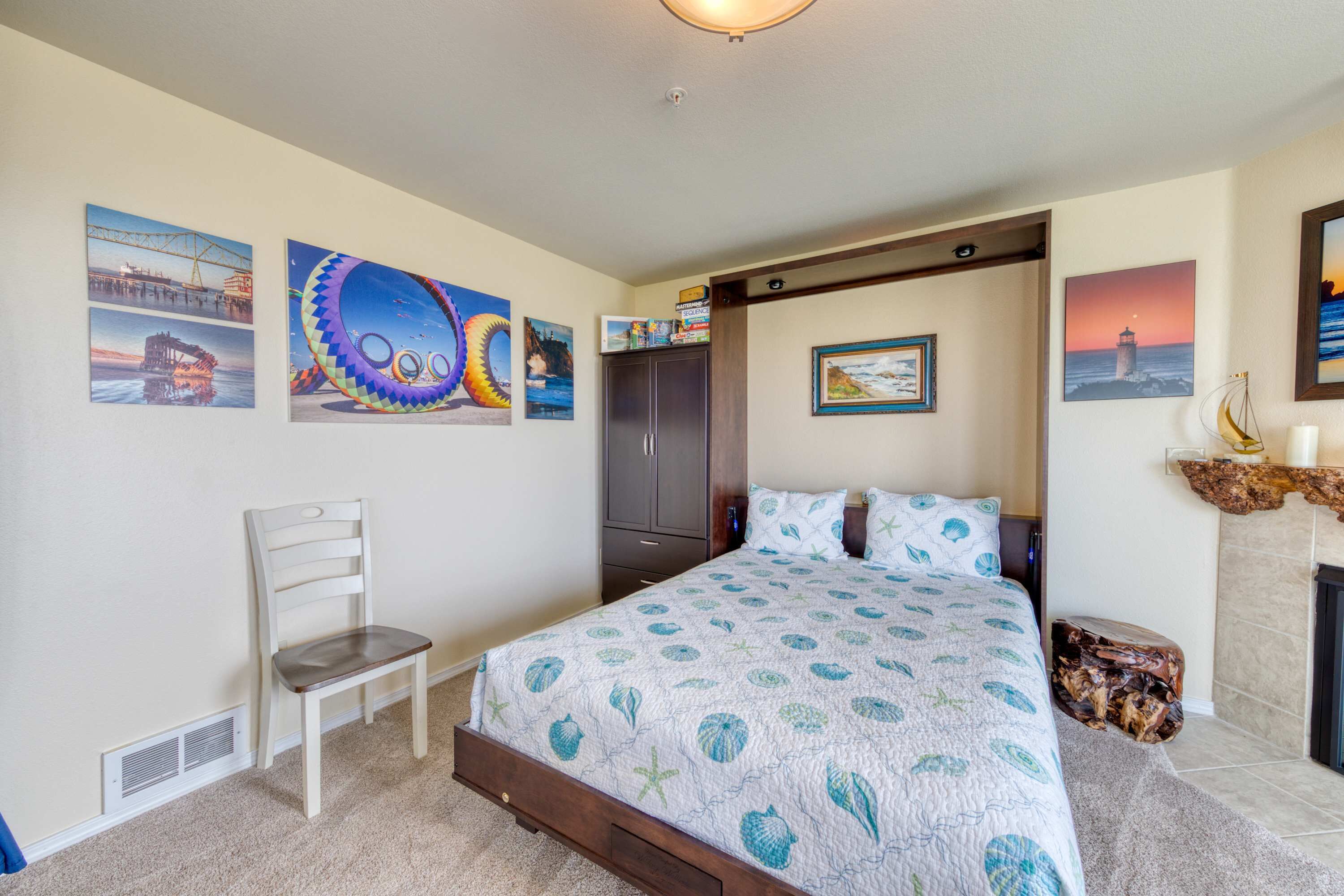 A bedroom with a bed, a chair, a wardrobe, and artwork on the walls.