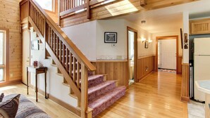 Un interior de madera con una escalera, una zona de cocina y un salón con un sofá.