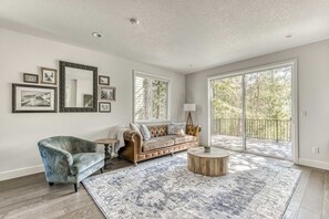 A spacious living room with a leather sofa, a blue armchair, and a large rug. - Government Camp Chalet -  Your Ultimate Ski Retreat in the Cascades (Government Camp)
