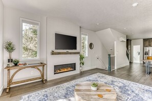 A living room with a fireplace, a TV mounted on the wall, and a staircase leading to another level. - Government Camp Chalet -  Your Ultimate Ski Retreat in the Cascades (Government Camp)