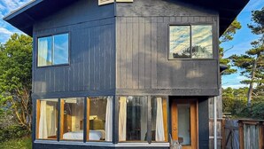 A two-story building with large windows and a visible interior bedroom. - Florence oceanfront escape, where cozy meets coastal charm (Florence)