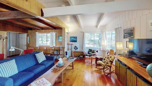A spacious living area with a blue sofa, wooden coffee table, and a television on a wooden stand. - Florence oceanfront escape, where cozy meets coastal charm (Florence)