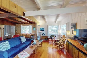 A spacious living area with a blue sofa, wooden coffee table, and a television on a wooden stand. - Florence oceanfront escape, where cozy meets coastal charm (Florence)