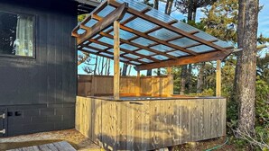 A wooden deck with a pergola structure, a wooden bench, and a hose on the ground. - Florence oceanfront escape, where cozy meets coastal charm (Florence)