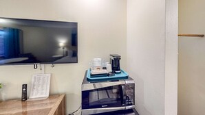 Un four à micro-ondes, une machine à café et une télécommande sont posés sur un comptoir, à côté d’un présentoir de menus.