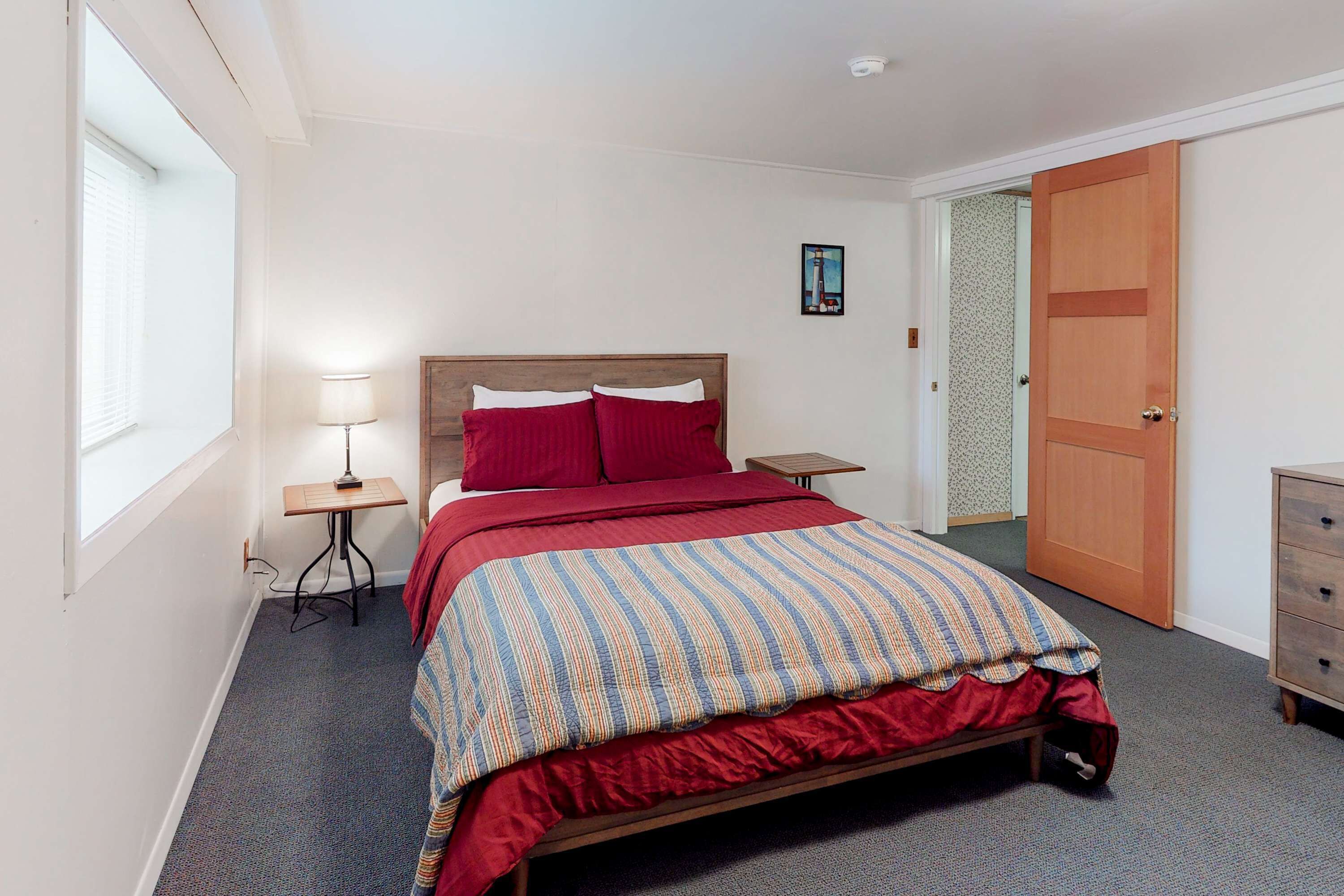 Une chambre à coucher avec un lit, une table de chevet, une lampe et une porte.