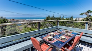 A dining table set for four with a view of the ocean. - Oceanview Home with Beautiful Deck & Private Playground - Blocks to the Beach (Newport)