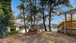 Un banco de madera cerca de un lago, una pasarela de madera y un puente al fondo.