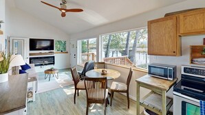 Una cocina moderna con comedor, armarios de madera, ventilador de techo, televisor y chimenea.