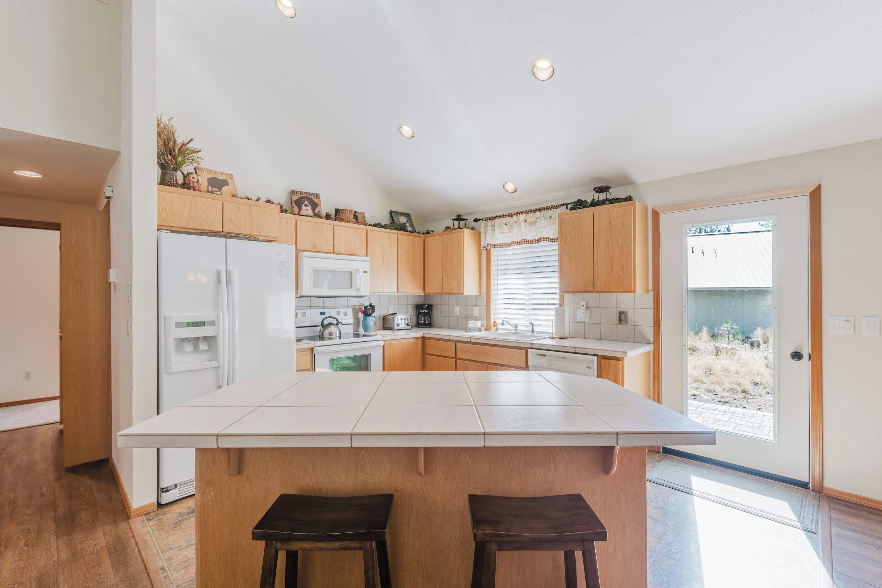 A modern kitchen with a central island, wooden cabinets, and built-in appliances.