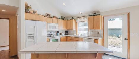 A modern kitchen with a central island, wooden cabinets, and built-in appliances.