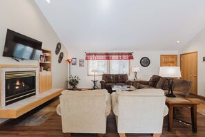 A living room with a fireplace, a television, a sofa, and a coffee table. - 4BR Sunriver Home with Private Hot Tub, SHARC Passes & EV Charger (Sunriver)