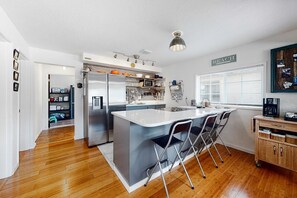 A modern kitchen with a central island, stainless steel appliances, and a view of the beach.