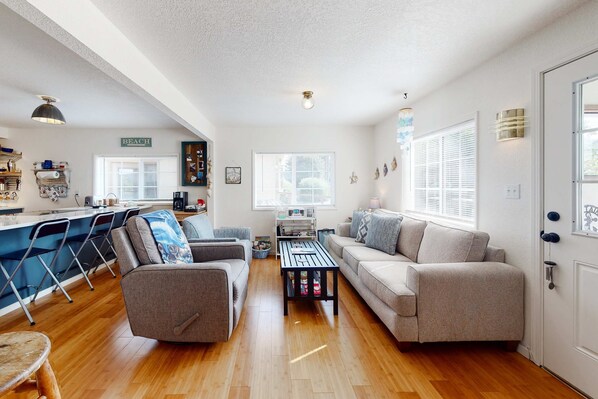 A spacious living area with a sofa, a coffee table, and a dining area with chairs and a counter.