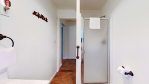 Un pasillo con una puerta blanca, un perchero y una lámpara de pared.