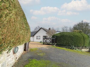 A house with a gravel driveway, a wooden gate, and a hedge. - Summerhill (Hereford)