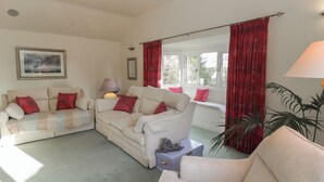 A living room with a sofa set, a lamp, a window with red curtains, and a framed picture on the wall. - Summerhill (Hereford)