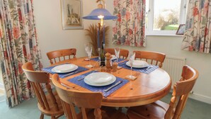 A round wooden dining table with blue placemats, surrounded by wooden chairs. - Summerhill (Hereford)