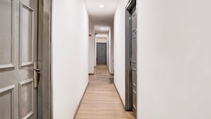 Un couloir étroit avec un plancher en bois, des murs blancs et des portes de chaque côté.