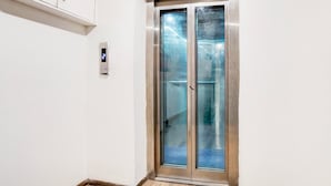 Un ascenseur moderne doté d’un écran numérique, de portes en verre et d’une structure métallique.