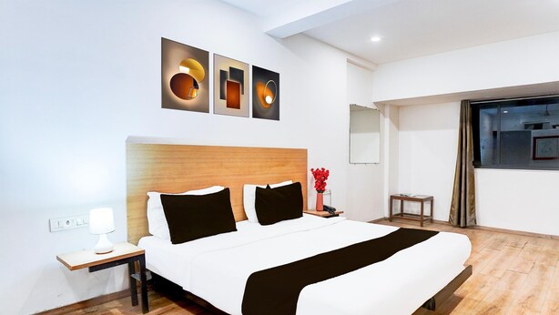 Une chambre d’hôtel moderne avec un grand lit, une table de chevet, une commode et une fenêtre avec des rideaux.
