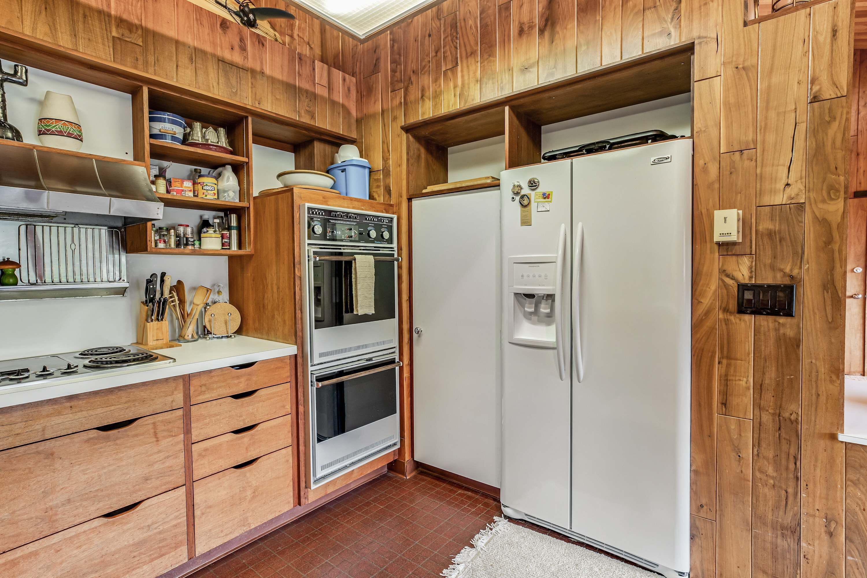 Une cuisine avec des meubles de rangement en bois, une cuisinière, un four et un réfrigérateur.