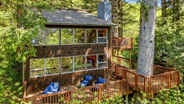 A two-story cabin with a deck, surrounded by trees. - Classic woodland home with gorgeous setting, great deck - 2 dogs OK (Nehalem)