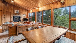 A wooden interior with a fireplace, large windows, and a dining area. - Classic woodland home with gorgeous setting, great deck - 2 dogs OK (Nehalem)