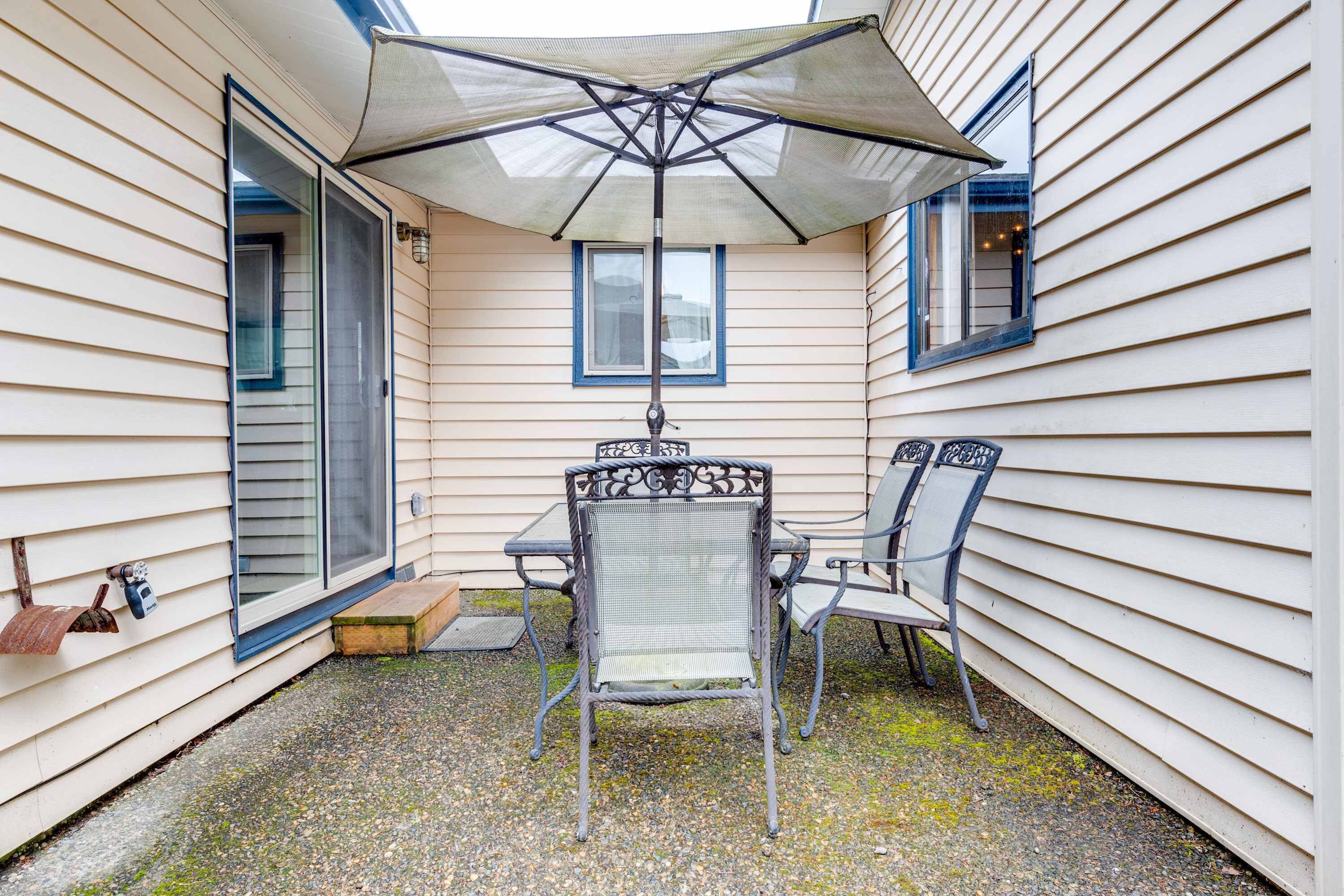 A patio with a table and chairs, a covered umbrella, and a window.