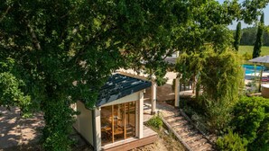 Una casa pequeña y moderna con puerta de vidrio, rodeada de árboles y un sendero.