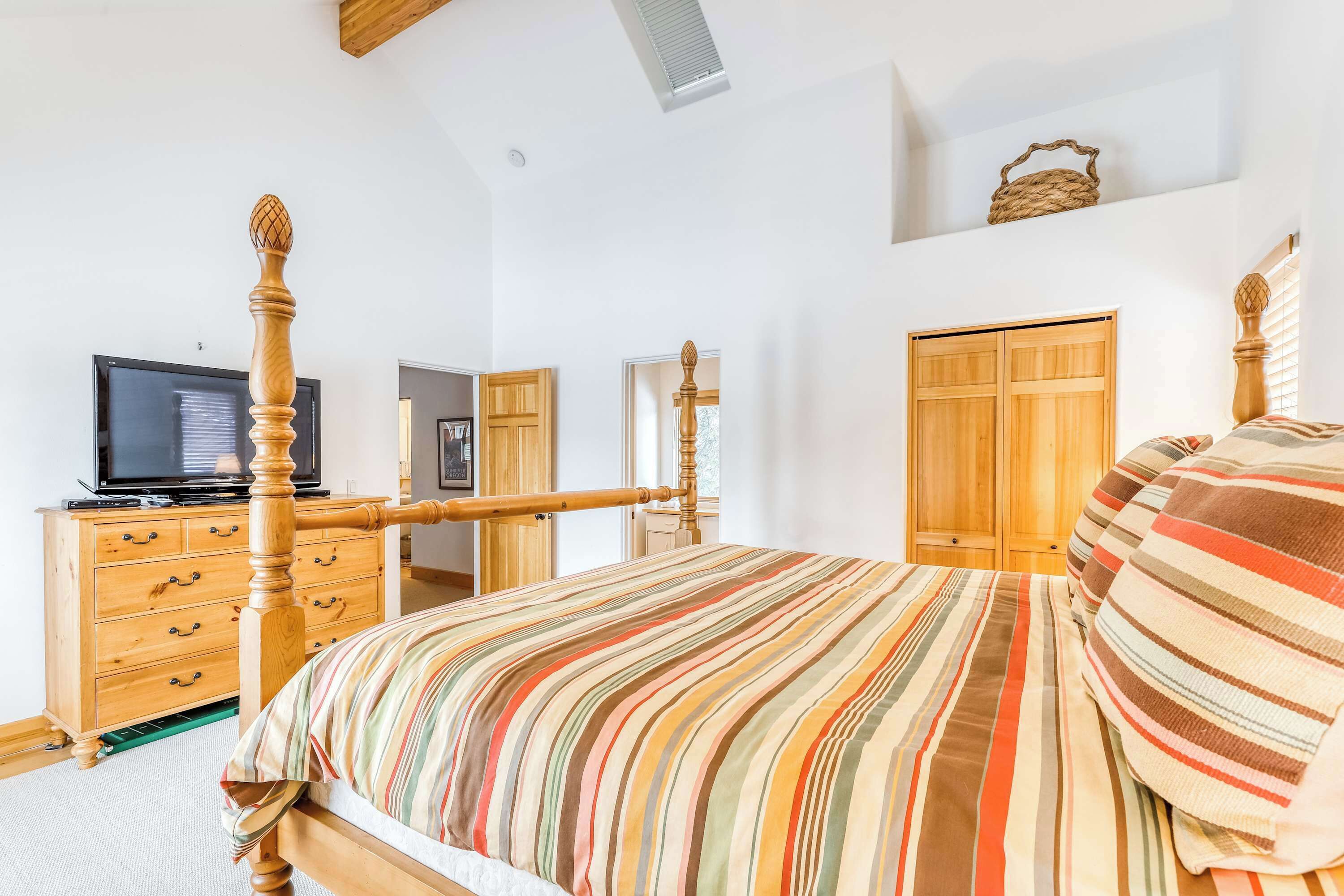 Un dormitorio con cama, cómoda de madera, televisor, armario y ventana.