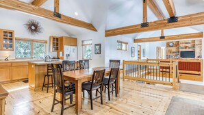 A spacious kitchen with wooden beams, a dining area with chairs, and a view of the outdoors. - Spacious dog friendly home withprivate hot tub, guest bikes, (Sunriver)