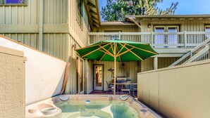 A hot tub with a green umbrella, a wooden deck, and a staircase leading to a balcony. - Spacious dog friendly home withprivate hot tub, guest bikes, (Sunriver)
