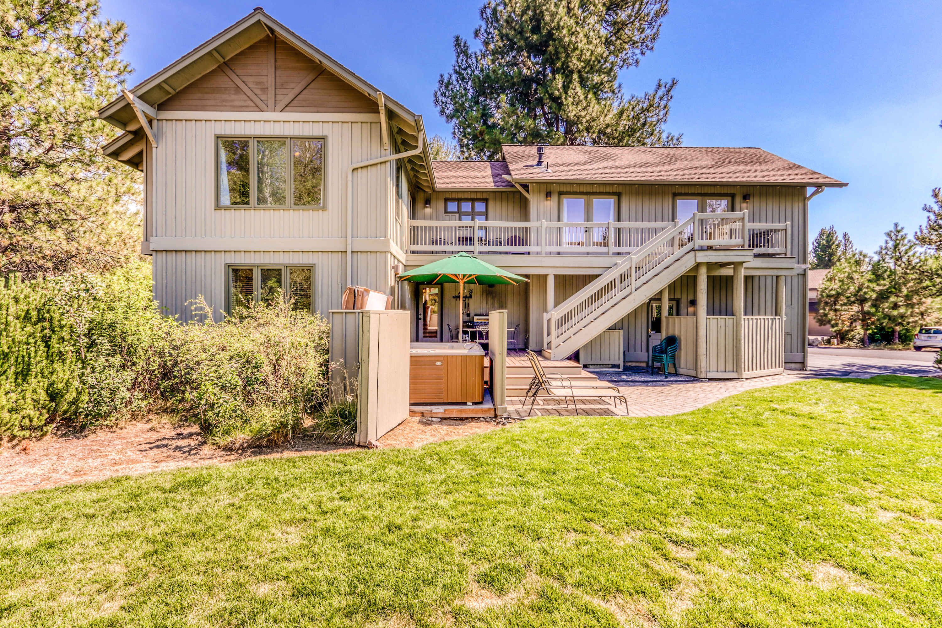 A two-story house with a balcony, a hot tub, and a covered patio area.