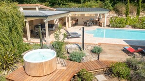 En baghave med swimmingpool, jacuzzi og en overdækket terrasse.