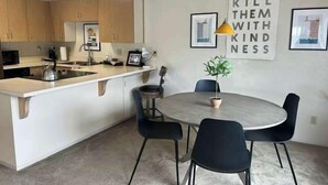 A modern kitchen with a central island, a dining area with a round table and chairs, and a motivational poster on the wall.
