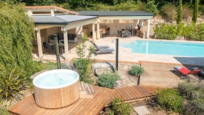 Ein Garten mit Schwimmbad, Whirlpool und überdachter Terrasse.