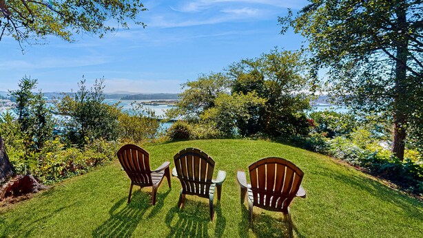 Three Adirondack chairs on a grassy lawn with a view of a body of water and distant landforms. - Bay & Harbor View Home with High-Speed WiFi, Private Washer/Dryer, & Board Games (Newport)